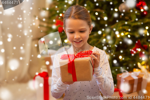 Image of smiling girl with christmas gift at home