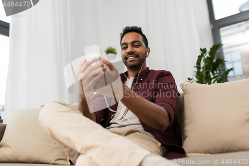 Image of man in earphones listening to music on smartphone