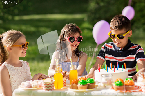 Image of happy kids with cake on birthday party at summer
