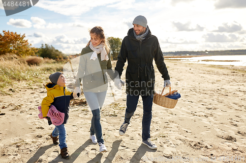 Image of happy family going to picnic on beach in autumn