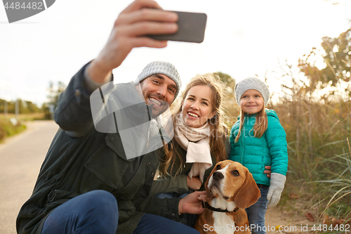 Image of happy family with dog taking selfie in autumn