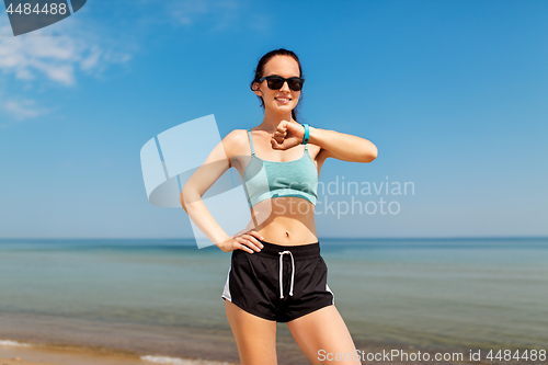 Image of happy woman with fitness tracker on summer beach