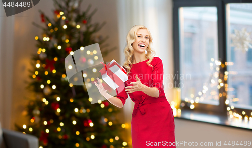 Image of happy woman in red dress with christmas gift