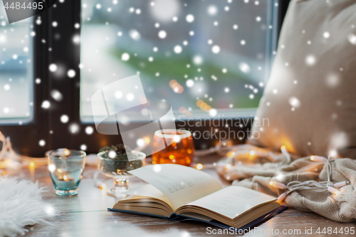 Image of book, garland lights and candles on window sill