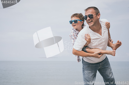 Image of Father and son playing on the beach at the day time.