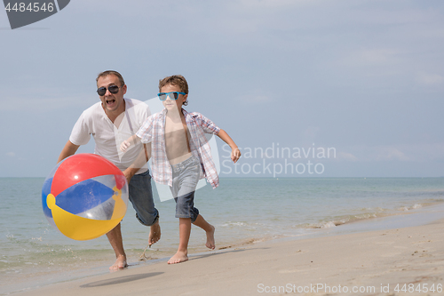 Image of Father and son playing on the beach at the day time.