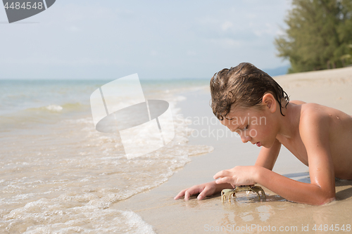 Image of One happy little boy playing on the beach at the day time.