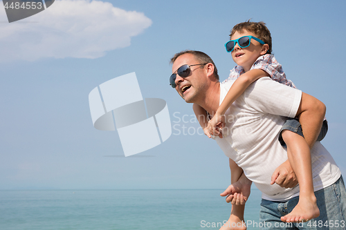 Image of Father and son playing on the beach at the day time.