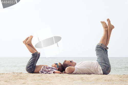 Image of Father and son playing on the beach at the day time.