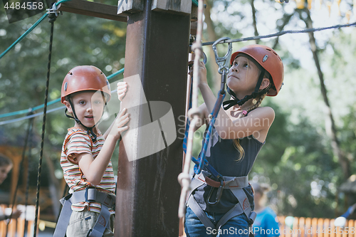 Image of little brother and sister make climbing in the adventure park.