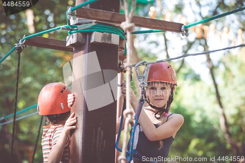 Image of little brother and sister make climbing in the adventure park.