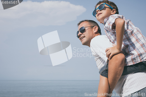 Image of Father and son playing on the beach at the day time.