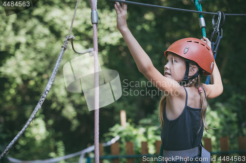 Image of little girl make climbing in the adventure park.