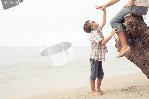 Image of Father and son playing on the beach at the day time.