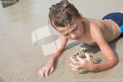 Image of One happy little boy playing on the beach at the day time.