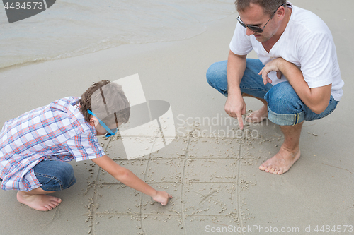 Image of Father and son playing on the beach at the day time.