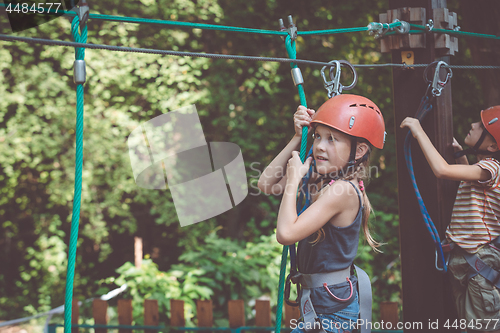 Image of little brother and sister make climbing in the adventure park.