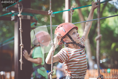 Image of little boy make climbing in the adventure park.