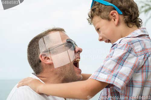 Image of Father and son playing on the beach at the day time.