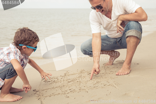 Image of Father and son playing on the beach at the day time.