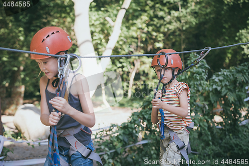 Image of little brother and sister make climbing in the adventure park.