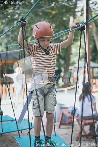 Image of little boy make climbing in the adventure park. 