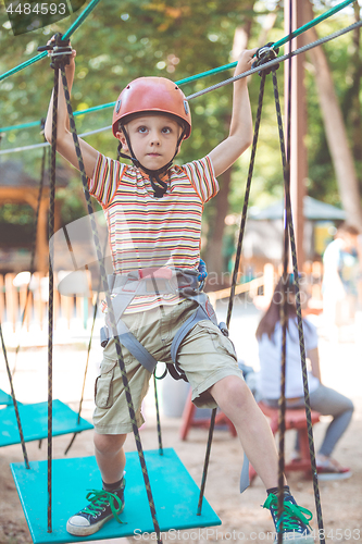 Image of little boy make climbing in the adventure park.