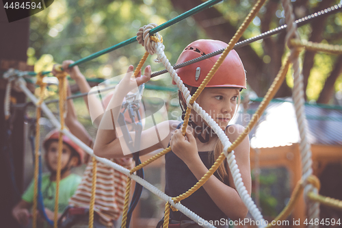 Image of little brother and sister make climbing in the adventure park.