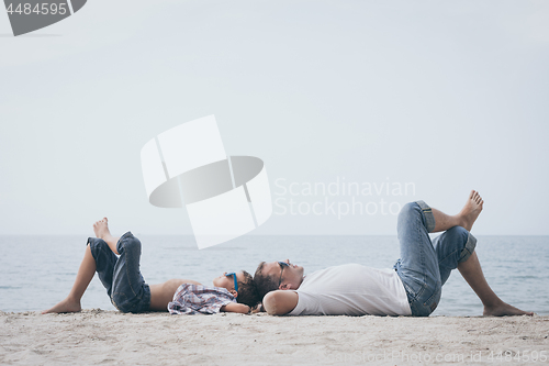 Image of Father and son playing on the beach at the day time.