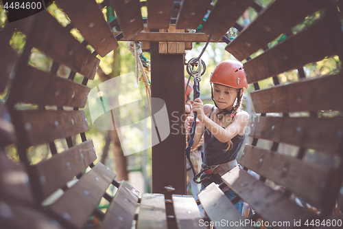 Image of little brother and sister make climbing in the adventure park.