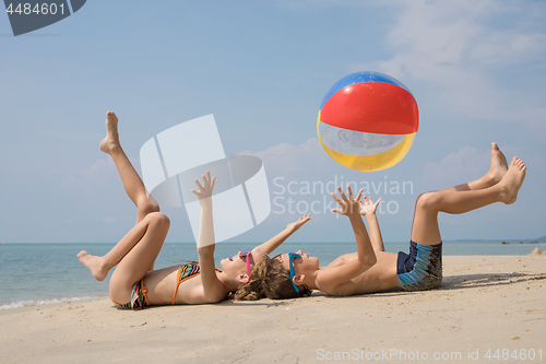 Image of Two happy little children playing on the beach at the day time.