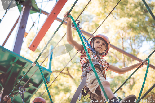 Image of little boy make climbing in the adventure park.