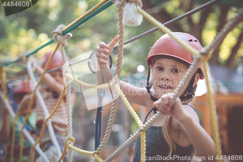 Image of little brother and sister make climbing in the adventure park.