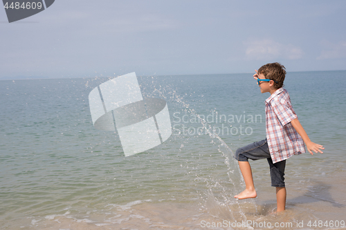 Image of One happy little boy playing on the beach at the day time.