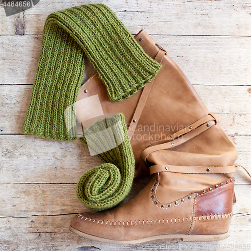 Image of brown leather high boot and knitted green wood legwarmers
