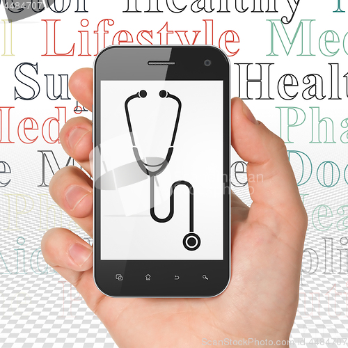 Image of Health concept: Hand Holding Smartphone with Stethoscope on display
