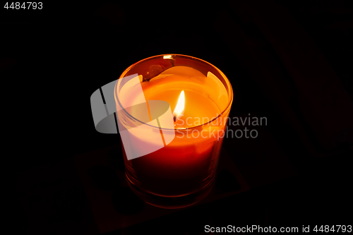 Image of A bright orange candle burning in the dark