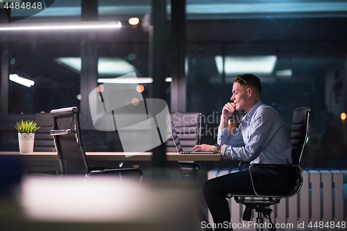 Image of man working on laptop in dark office