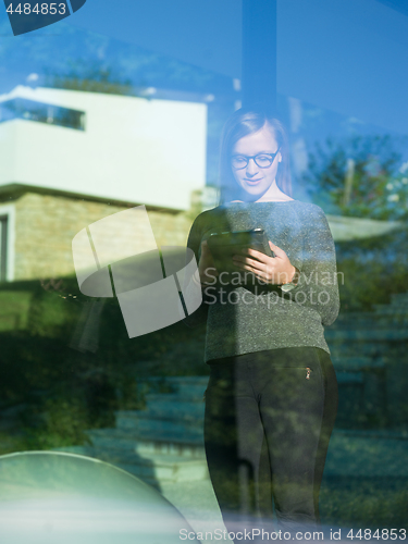 Image of Woman using tablet at home by the window