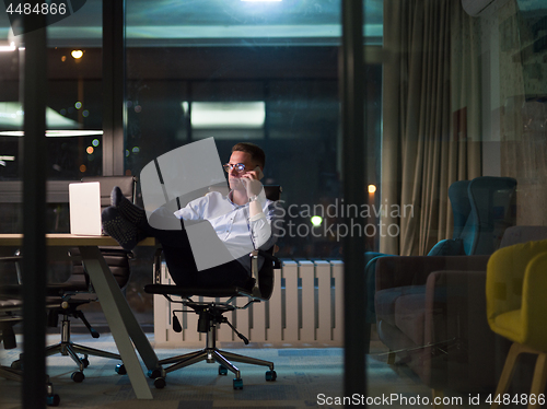 Image of businessman using mobile phone in dark office