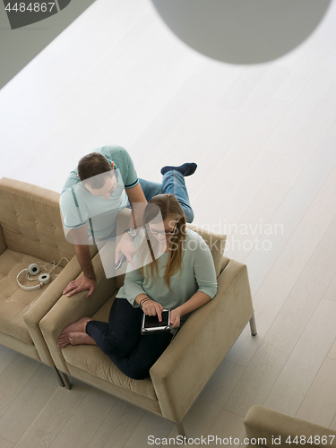 Image of couple relaxing at  home with tablet computers