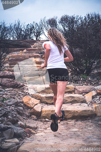 Image of Fit active woman running up stairs in outdoor landscape