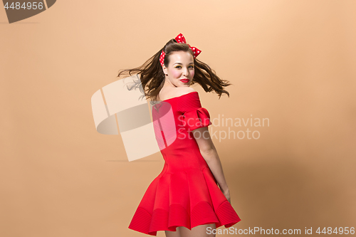 Image of Beautiful young woman with pinup make-up and hairstyle. Studio shot on pastel background