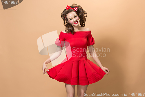 Image of Beautiful young woman with pinup make-up and hairstyle. Studio shot on pastel background