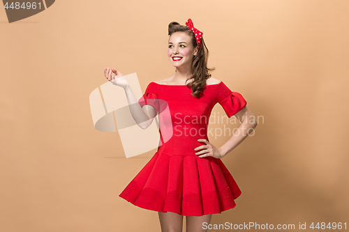 Image of Beautiful young woman with pinup make-up and hairstyle. Studio shot on pastel background