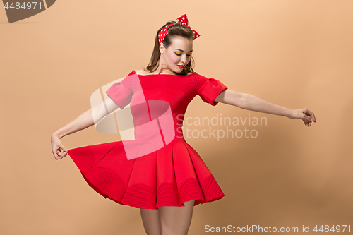 Image of Beautiful young woman with pinup make-up and hairstyle. Studio shot on pastel background