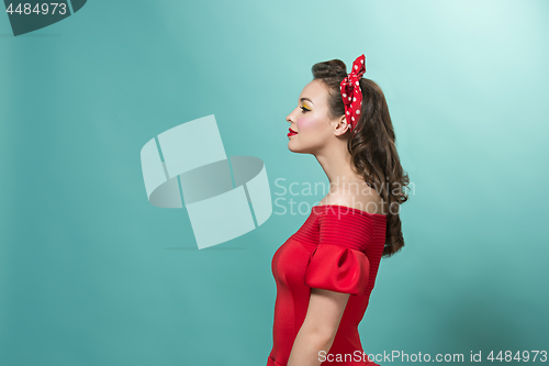 Image of Beautiful young woman with pinup make-up and hairstyle. Studio shot on pastel background