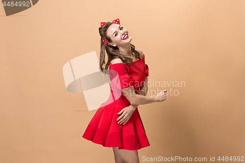 Image of Beautiful young woman with pinup make-up and hairstyle. Studio shot on pastel background