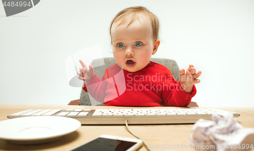 Image of Happy child baby girl toddler sitting with keyboard of computer isolated on a white background