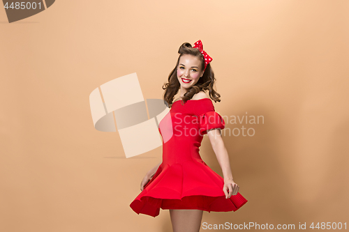 Image of Beautiful young woman with pinup make-up and hairstyle. Studio shot on pastel background